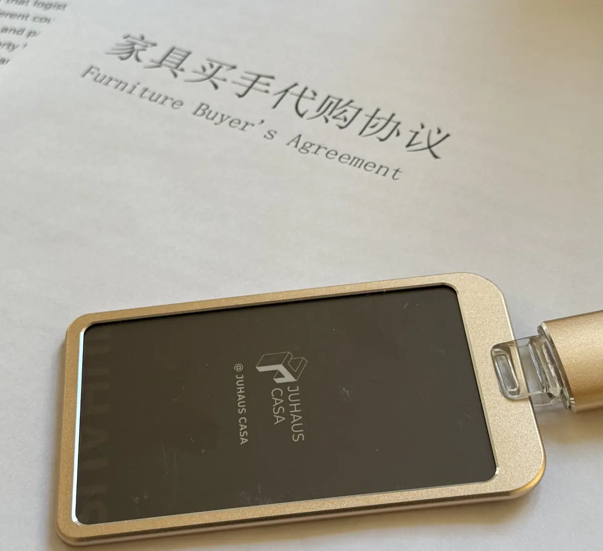 Photographed title of a Furniture Buyer's Agreement beside a Juhaus brand token