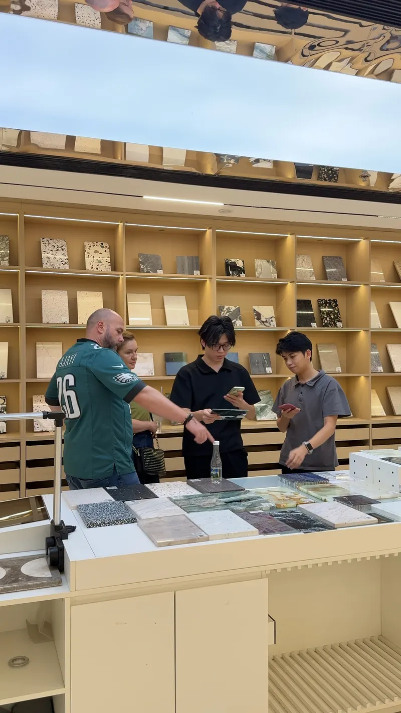 Four adults compare stone-like surface samples arranged across a counter.