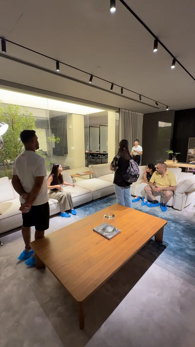 Several people gather around a light sofa arrangement and a low table in a showroom.